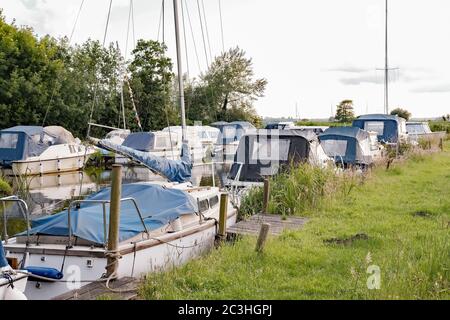 Sportboote und Motorboote liegen im Thurne Dyke im Norfolk Broads National Park Stockfoto
