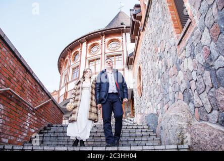 Ein paar Brautpaare gehen am frühen Frühlingstag in der Nähe der alten Burg Stockfoto