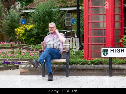 Beckenham, Großbritannien, 20. Juni 2020,EIN Mann sitzt auf einer einzigen Holzbank in Beckenham High Street, Kent. Die Hauptstraße ist viel belebter, jetzt, da viele nicht wesentliche Geschäfte wieder geöffnet haben.Quelle: Keith Larby/Alamy Live News Stockfoto