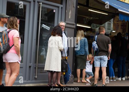 Beckenham, Großbritannien, 20. Juni 2020, die Menschen folgen den Regeln der sozialen Distanzierung, während sie Schlange stehen, um in die Geschäfte in Beckenham High Street, Kent zu gehen. Die Hauptstraße ist viel belebter, jetzt, da viele nicht wesentliche Geschäfte wieder geöffnet haben.Quelle: Keith Larby/Alamy Live News Stockfoto