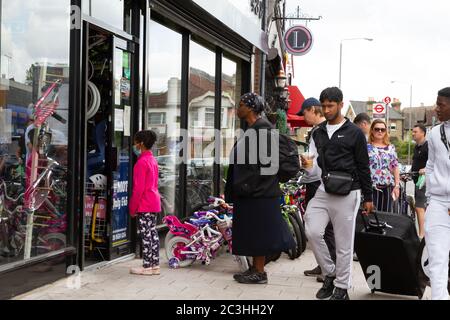 Beckenham, Großbritannien, 20. Juni 2020, die Menschen folgen den Regeln der sozialen Distanzierung, während sie Schlange stehen, um in die Geschäfte in Beckenham High Street, Kent zu gehen. Die Hauptstraße ist viel belebter, jetzt, da viele nicht wesentliche Geschäfte wieder geöffnet haben.Quelle: Keith Larby/Alamy Live News Stockfoto