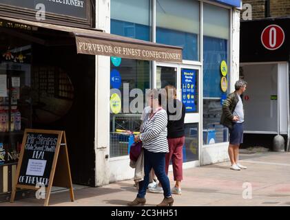 Beckenham, Großbritannien, 20. Juni 2020, die Menschen folgen den Regeln der sozialen Distanzierung, während sie Schlange stehen, um in die Geschäfte in Beckenham High Street, Kent zu gehen. Die Hauptstraße ist viel belebter, jetzt, da viele nicht wesentliche Geschäfte wieder geöffnet haben.Quelle: Keith Larby/Alamy Live News Stockfoto