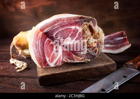 Spanischer Schinken, bellota, Jamon serrano, Crudo, italienischer Schinken, ganzes Bein, parmaschinken mit einem Messer geschnitten und auf einem Holzbrett liegend. Nahaufnahme Stockfoto