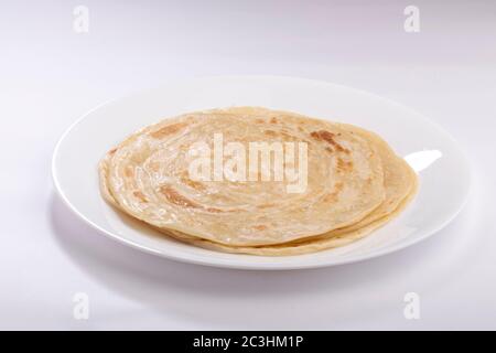 Hausgemachtes Kerala Parotta/ Porotta /Paratta /geschichtetes Fladenbrot mit maida oder raffiniertem Mehl oder Allzweckmehl, das wunderschön auf einem weißen Teller angeordnet ist Stockfoto