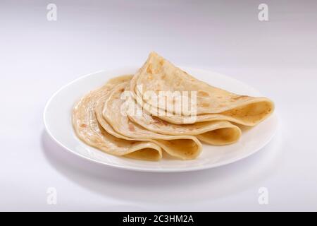 Hausgemachtes Kerala Parotta/ Porotta /Paratta /geschichtetes Fladenbrot mit maida oder raffiniertem Mehl oder Allzweckmehl, das wunderschön auf einem weißen Teller angeordnet ist Stockfoto