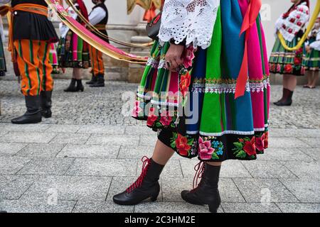 Menschen in polnischen Volkstrachten aus der Region Lowicz während der jährlichen Fronleichnamsprozession. Nahaufnahme von traditionellen gestreiften Rock Stockfoto