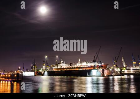 Nachtaufnahme von Dock mit großem Containerschiff an der Elbe in Hamburg Stockfoto