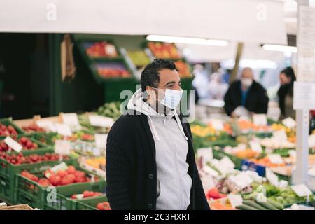 MÜNCHEN, 02. Mai 2020: Bauer verkauft seine frische Ernte auf dem Bauernmarkt. Er trägt eine Gesichtsmaske, um sich vor dem Coronavirus (Covid- Stockfoto