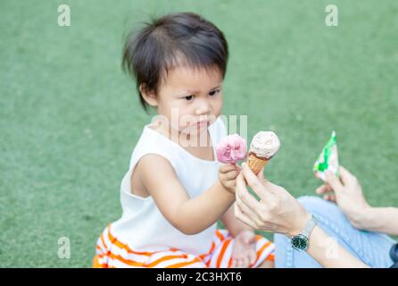 asiatische Kind und Mutter essen Eis zusammen im Park Stockfoto