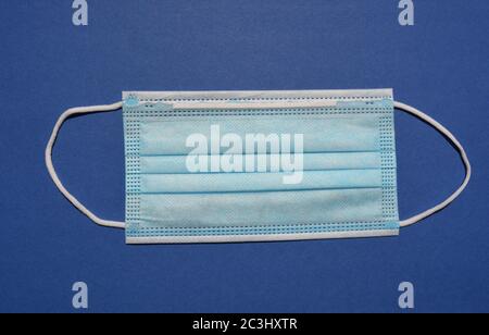 Einweg-3-lagige nicht-chirurgische Gesichtsmaske mit elastischen Ohrschlaufen isoliert auf blauem Hintergrund Stockfoto