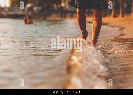 Ein Mann, der am Strand und am Meereswasser in der Sonnenuntergangszeit läuft. Stockfoto