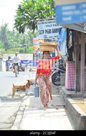 Frau mit einem Korb auf dem Kopf auf dem Ubud-Markt in Bali, Indonesien. Stockfoto