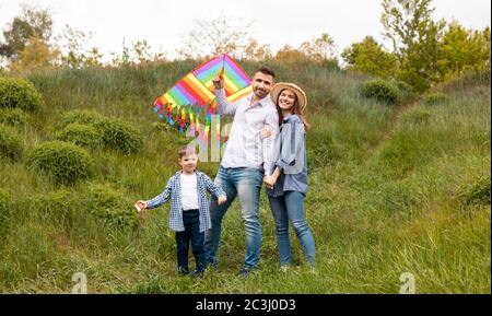 Portrait der glücklichen Familie mit hellen Drachen in der Landschaft Stockfoto