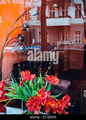 Vertikale Aufnahme von roten Mohnblumen auf einem Fensterhintergrund mit Ein Spiegelbild der Straße Stockfoto