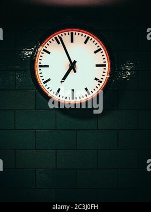 Nahaufnahme einer U-Bahn-Wanduhr, die die Zeit anzeigt. Vier Minuten bis sieben Stockfoto