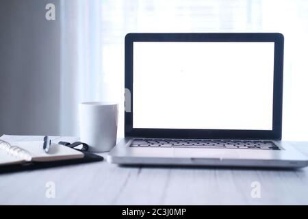 Laptop mit leerem Bildschirm und weißem Kaffeebecher auf dem Schreibtisch Stockfoto
