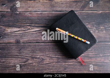 Ansicht von oben auf dem Holztisch mit geschlossenem Tagebuch und Stift Stockfoto
