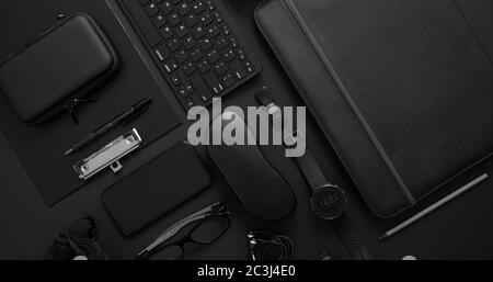 Geschäftskonzept. Flach Lay Zusammensetzung mit verschiedenen schwarzen Gadgets. Computertastatur, Smartphone, Ledertasche, Brille auf dunkelschwarzer Oberfläche. Busin Stockfoto