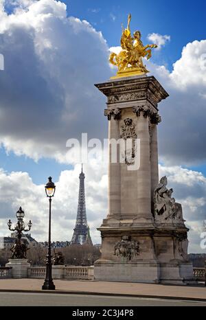 Säule mit vergoldeter Skulptur auf der Brücke Pont Alexandre III mit dem Eiffelturm im Hintergrund. Paris, Frankreich. Stockfoto