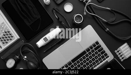 Doctor Desktop-Konzept. Verschiedene medizinische Werkzeuge und Zubehör auf schwarzem Hintergrund Tisch als Modell platziert. Mit Laptop, Medizin, Stethoskop, Pressu Stockfoto