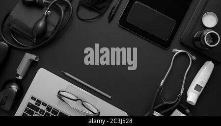 Doctor Desktop-Konzept. Verschiedene medizinische Werkzeuge und Zubehör auf schwarzem Hintergrund Tisch als Modell platziert. Mit Laptop, Medizin, Stethoskop, Pressu Stockfoto