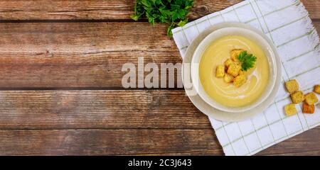 Hausgemachte cremige Gemüsesuppe mit Croutons auf Holztisch. Stockfoto