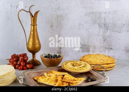 Hummus mit Oliven-, Traube- und Pita-Brot auf weißem Hintergrund. Stockfoto