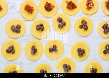 Runde Teigkekse mit Schokoladenstückchen und Marmelade zum Backen vorbereitet. Stockfoto