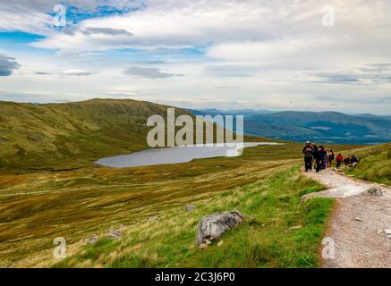 Ben Nevis / UK - August 24 2019: Menschen wandern auf Ben Nevis in den schottischen Highlands mit loch Lochan Meall an t-Suidhe im Hintergrund. Stockfoto