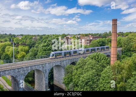 Luas Green Line Straßenbahn über das Viadukt Nine Arches Bridge über den Dodder Fluss in Milltown, Dublin. Stockfoto