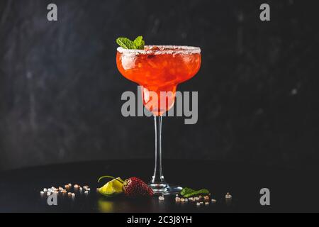 Gefrorene Erdbeer Limette Minze margarita in hohen Fuß Glas auf dem dunklen Hintergrund. Luxus Alkohol frisches Getränk Stockfoto