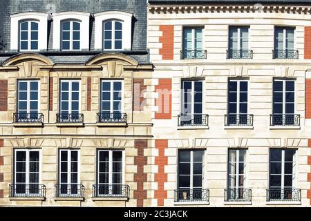 Typische Pariser Architektur. Die Fassade eines roten Ziegelgebäudes in Paris zeigt Fensterdetails mit schmiedeeisernen Geländern. Stockfoto