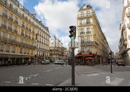 PARIS, FRANKREICH - 2. MÄRZ: Geschäftige Straßenszene im Zentrum von Paris, mit Geschäften und einem Straßencafé, mit typischer Pariser Architektur Stockfoto