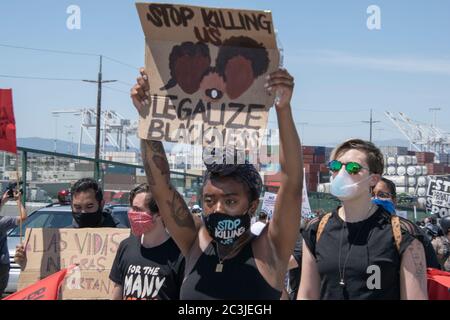 Ein Protestler trägt ein Schild, auf dem steht: "Tötet uns" bei einem Protest von Black Lives Matter am 19. Juni 2020 im Hafen von Oakland. Stockfoto