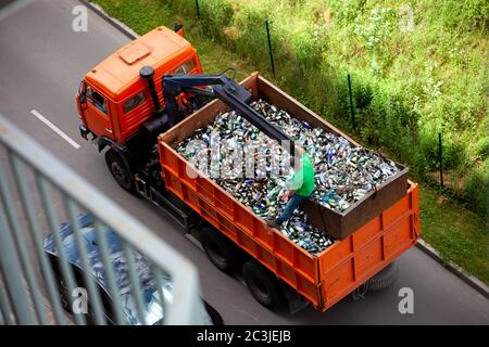 Der Muldenkipper nimmt Glasflaschen zum Recycling heraus. Recycling-Sortierung. Abfallrecycling. Keine Verschwendung. Viele Flaschen. Ansicht von oben. Müllwagen Stockfoto