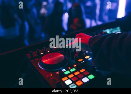 Produzent DJ Mixer in einem Nachtclub mit glühenden spielt musikalische Rave Dubstep Elektronische Trance Komposition mit modernen Midi-Controller-Gerät in Nightglu Stockfoto
