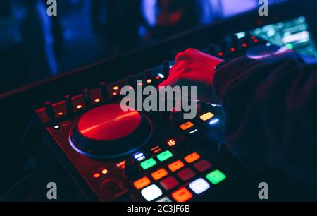 Produzent DJ Mixer in einem Nachtclub mit glühenden spielt musikalische Rave Dubstep Elektronische Trance Komposition mit modernen Midi-Controller-Gerät in Nightglu Stockfoto