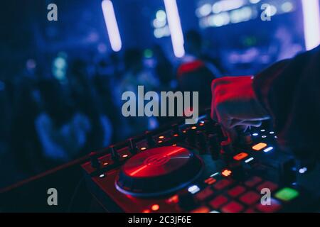 Produzent DJ Mixer in einem Nachtclub mit glühenden spielt musikalische Rave Dubstep Elektronische Trance Komposition mit modernen Midi-Controller-Gerät in Nightglu Stockfoto