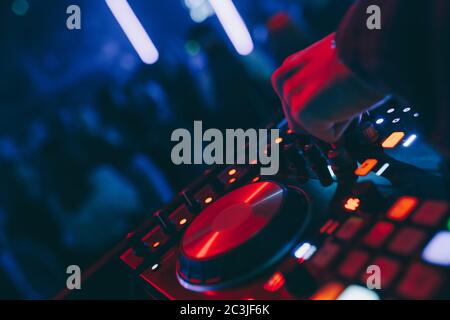 Produzent DJ Mixer in einem Nachtclub mit glühenden spielt musikalische Rave Dubstep Elektronische Trance Komposition mit modernen Midi-Controller-Gerät in Nightglu Stockfoto