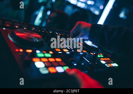 Produzent DJ Mixer in einem Nachtclub mit glühenden spielt musikalische Rave Dubstep Elektronische Trance Komposition mit modernen Midi-Controller-Gerät in Nightglu Stockfoto