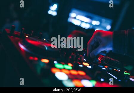 Produzent DJ Mixer in einem Nachtclub mit glühenden spielt musikalische Rave Dubstep Elektronische Trance Komposition mit modernen Midi-Controller-Gerät in Nightglu Stockfoto