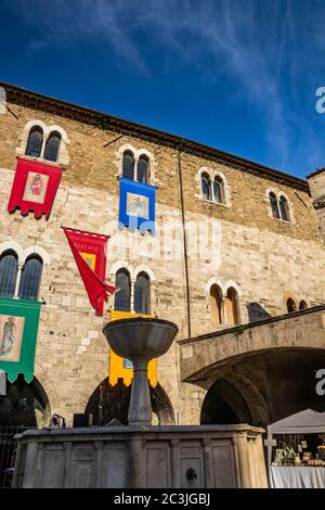 1. Juni 2019 - Bevagna, Perugia, Umbrien, Italien. Der mittelalterliche Palazzo dei Consoli im Dorf Bevagna. Mauer aus Stein und Ziegel. Die Banner des d Stockfoto