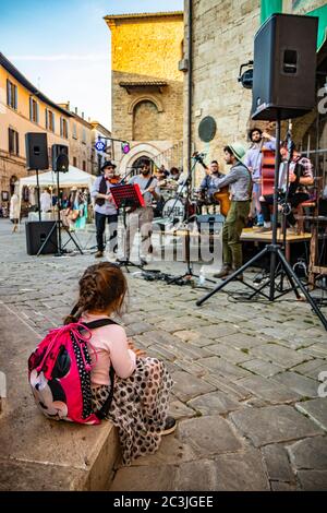 1. Juni 2019 - Bevagna, Perugia, Umbrien, Italien. Ein kleines Mädchen mit einem Zopf, bewundernswert, das eine Bandshow ansieht. Konzert von Straßenkünstlern während eines Amboss Stockfoto