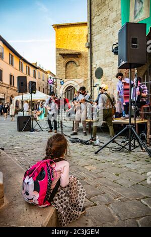 1. Juni 2019 - Bevagna, Perugia, Umbrien, Italien. Ein kleines Mädchen mit einem Zopf, bewundernswert, das eine Bandshow ansieht. Konzert von Straßenkünstlern während eines Amboss Stockfoto