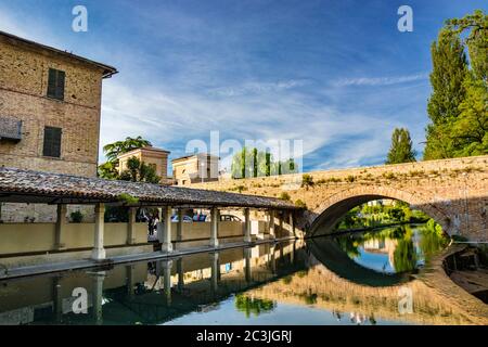 1. Juni 2019 - Bevagna, Perugia, Umbrien, Italien. Das alte Waschhaus und die gemauerte Brücke über den Fluss, im mittelalterlichen Dorf Bevagna. Blau Stockfoto