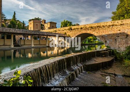 1. Juni 2019 - Bevagna, Perugia, Umbrien, Italien. Das alte Waschhaus und die gemauerte Brücke über den Fluss, im mittelalterlichen Dorf Bevagna. Blau Stockfoto