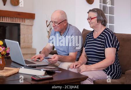 Ältere Paare, die online mit Kreditkarte zu Hause auf dem Laptop einkaufen. Internet-Banking zu Hause Konzept. Konzentrieren Sie sich auf das Gesicht eines älteren Mannes Stockfoto