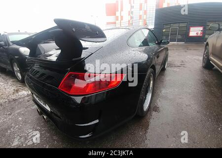 Moskau, Russland - 22. April 2019: Ein schwarzer Porsche 911, der mit Aerodynamik-Kit und Carbon-Spoiler ausgestattet ist, steht auf dem Parkplatz des Service-Centers. Regen fällt auf das Auto. Rückseite Ansicht Stockfoto