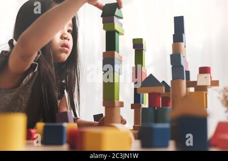 Happy Little girl spielen Spiel Gebäude Konstruktor Turm aus bunten Holzblöcken. Lern-und Entwicklungshintergrund Konzept. Stockfoto