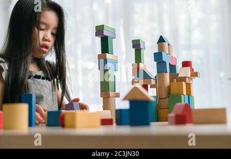 Happy Little girl spielen Spiel Gebäude Konstruktor Turm aus bunten Holzblöcken. Lern-und Entwicklungshintergrund Konzept. Stockfoto